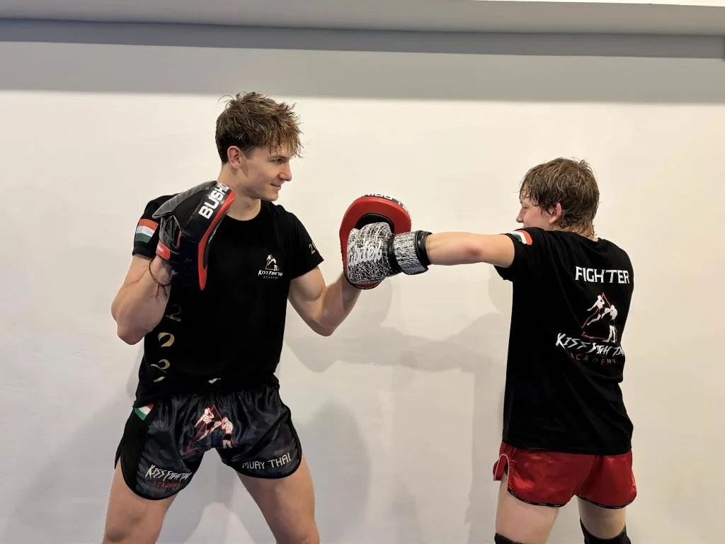 Gyerek edzés a Kiss Fighting Academyn: fiatal tanítvány ütést gyakorol Barni edző által tartott padon