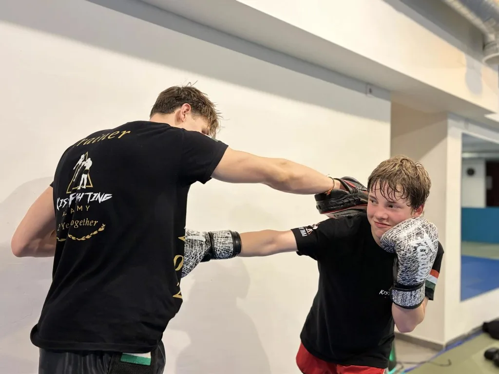 Barni edző mosolyogva tartja a padot egy vidám tanítványnak